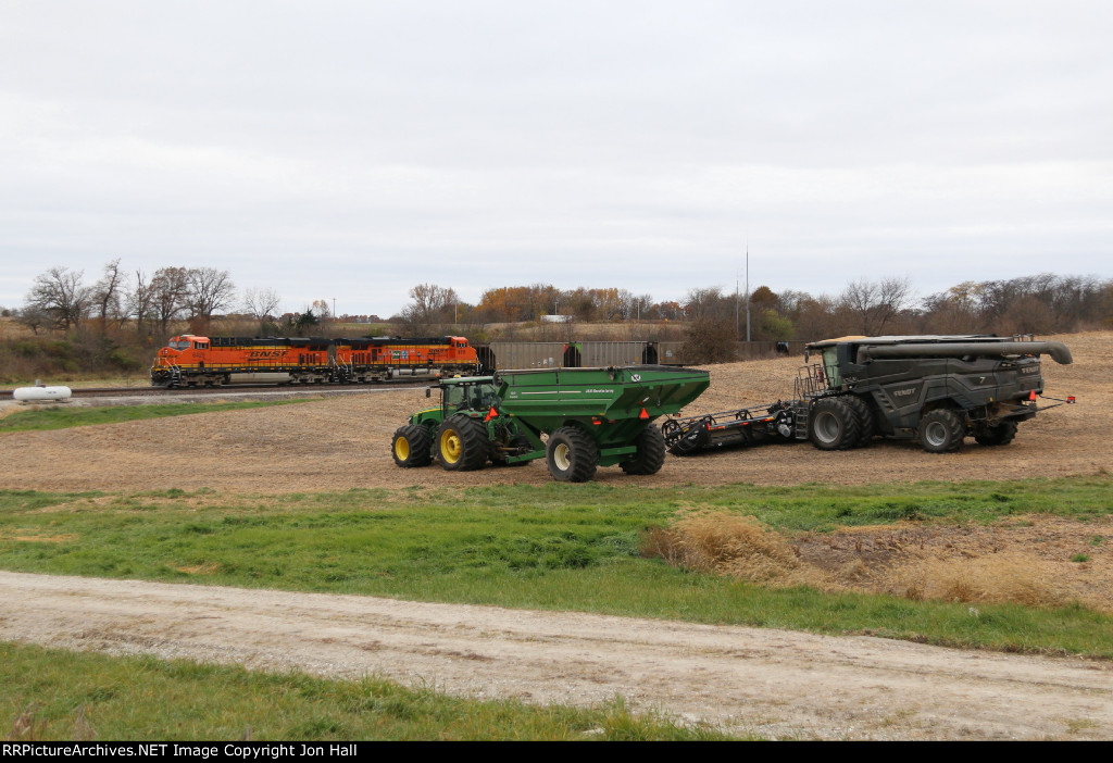 Farm equipment waiting for the final days of the 2021 harvest sit in a field as another coal empty passes